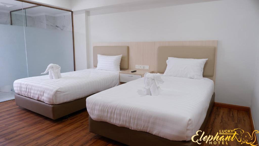Ban Bang Toei (1)的住宿－Lucky Elephant Hotel，客房内的两张床和白色床单