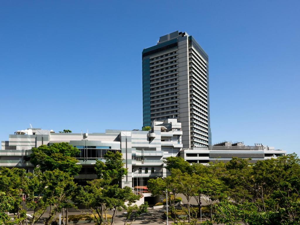 Grand Prince Hotel Osaka Bay في أوساكا: مبنى طويل وبه أشجار أمامه