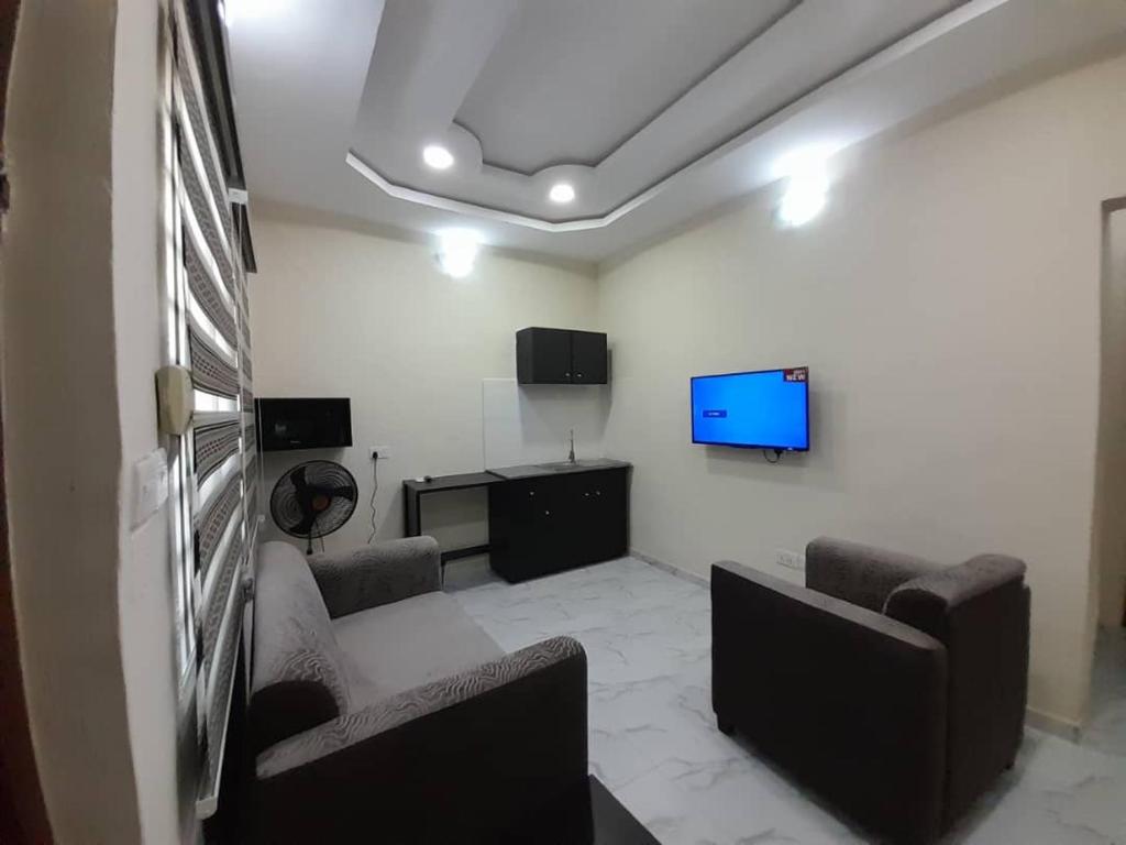 Habitación con sillas y TV. en F and B serviced apartment Abeokuta, en Aro