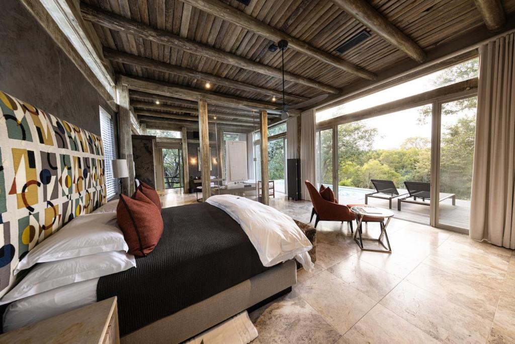ein Schlafzimmer mit einem großen Bett in einem Zimmer mit großen Fenstern in der Unterkunft Kapama Karula in Kapama Private Game Reserve