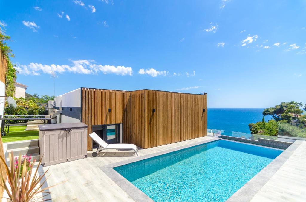 une piscine avec une chaise et l'océan en arrière-plan dans l'établissement Villa Casa Blanca - Location Maitikoa, à Lloret de Mar