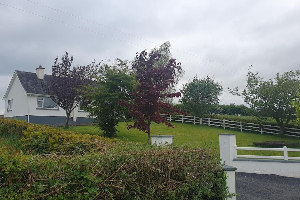 a white house with a white fence and a yard at 3 bedroom house close to lough sheelin in Cavan