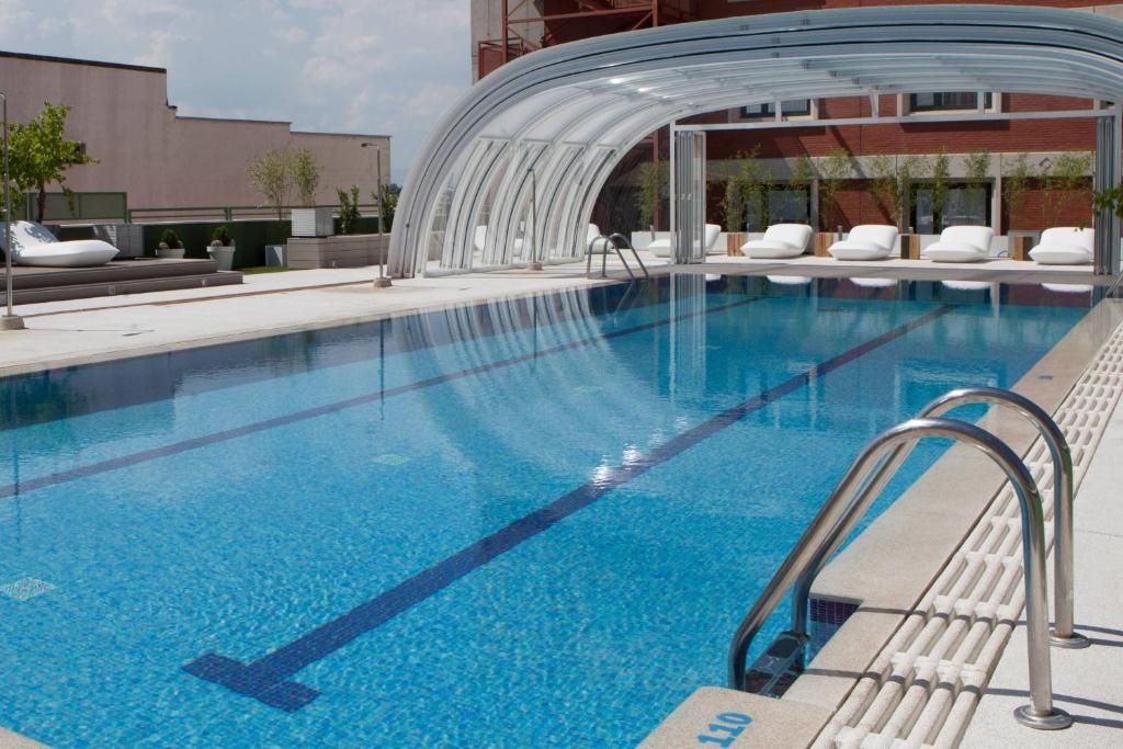 a large swimming pool with blue water in a building at Madrid Marriott Auditorium Hotel & Conference Center in Madrid