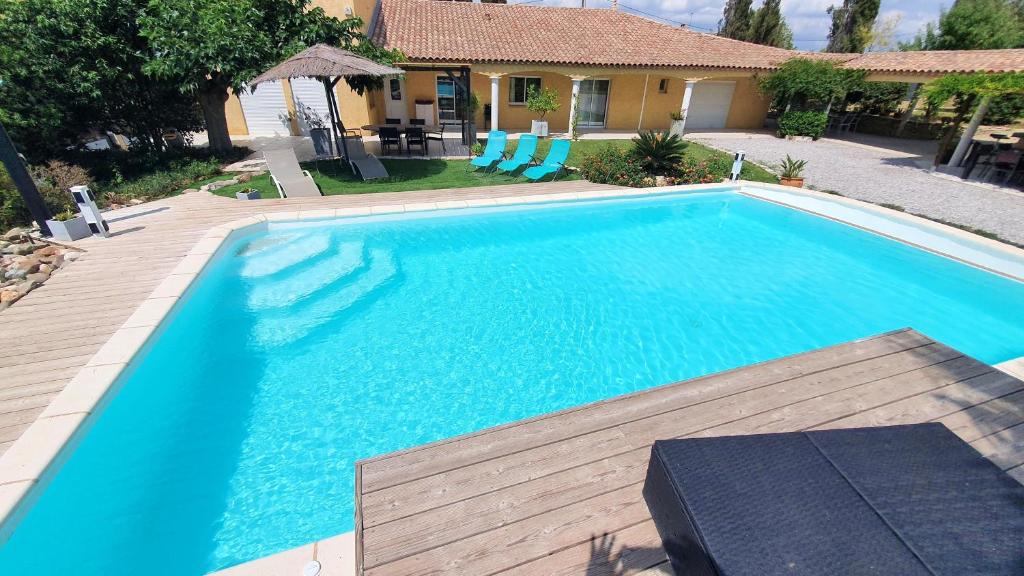 une grande piscine bleue à côté d'une maison dans l'établissement Villa de 6 chambres avec piscine privee jacuzzi et jardin clos a Beziers, à Béziers