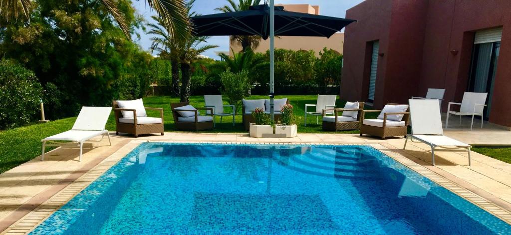 a swimming pool with lounge chairs and an umbrella at 3 bedrooms villa at La Marsa 400 m away from the beach with private pool enclosed garden and wifi in La Marsa