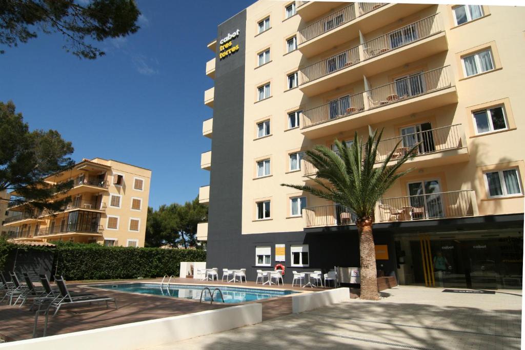 a hotel with a palm tree in front of a building at Cabot Tres Torres Apartamentos in Playa de Palma