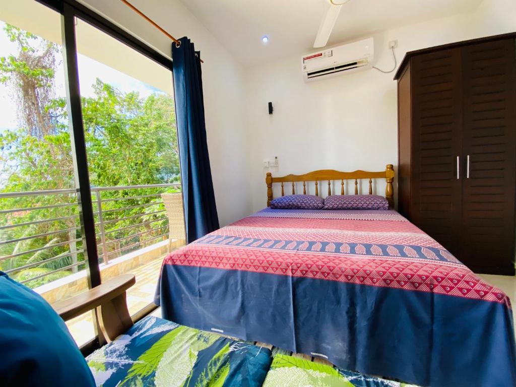 a bedroom with a bed and a large window at Oceanic View Lodges in Bel Ombre