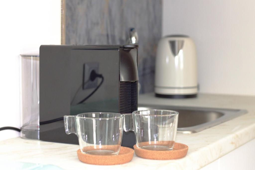a coffee maker and two glasses on a counter at Cottage Boutique Apartments Athens in Athens
