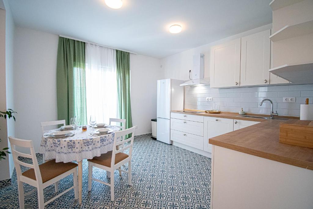 a kitchen with a table and chairs and a kitchen with white cabinets at Apartment Nikola in Kastel Novi