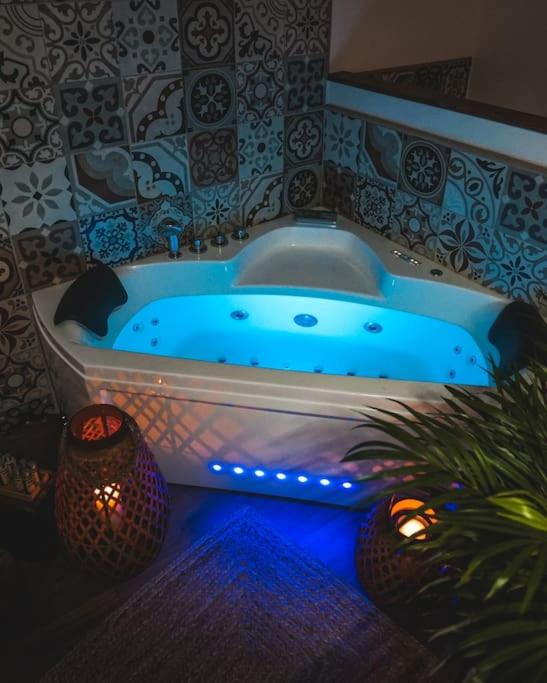 La salle de bains est pourvue d'une baignoire bleue éclairée. dans l'établissement Appartement cosy, à Sahorre