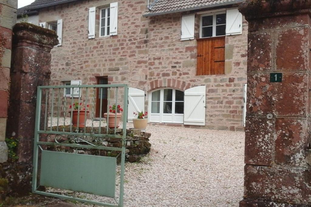 a brick house with a gate in front of it at Gite les Noyers in Noailhac