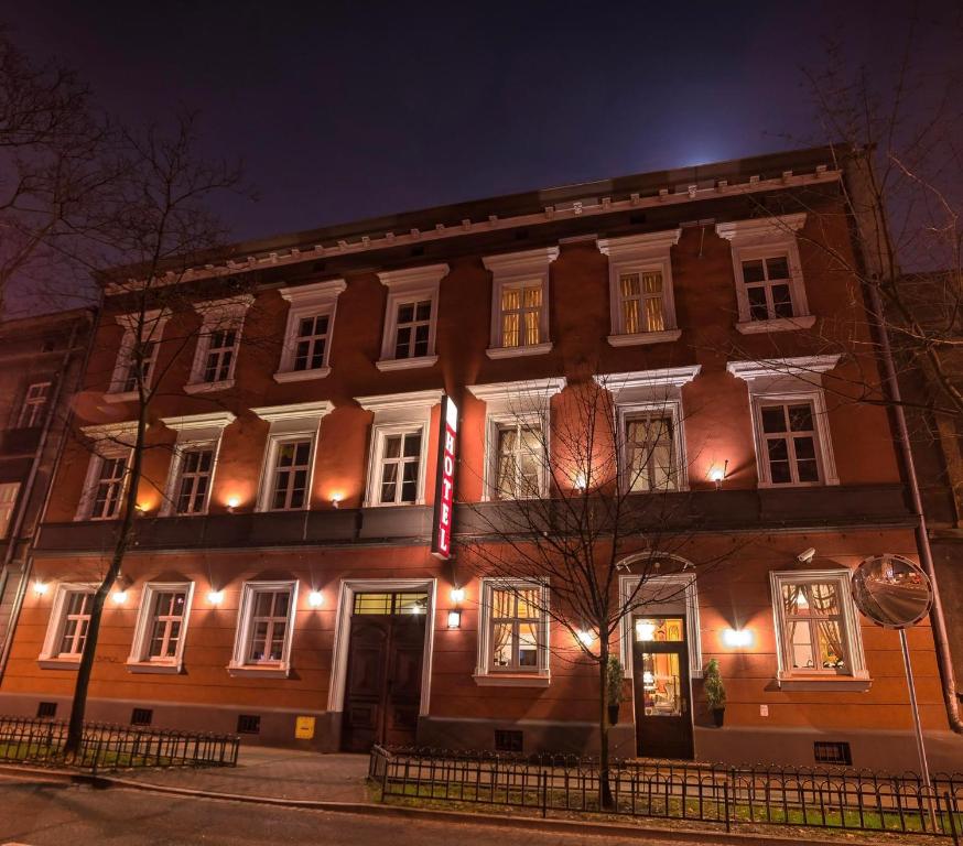 un gran edificio de ladrillo con luces encendidas por la noche en Old Time Hotel en Cracovia