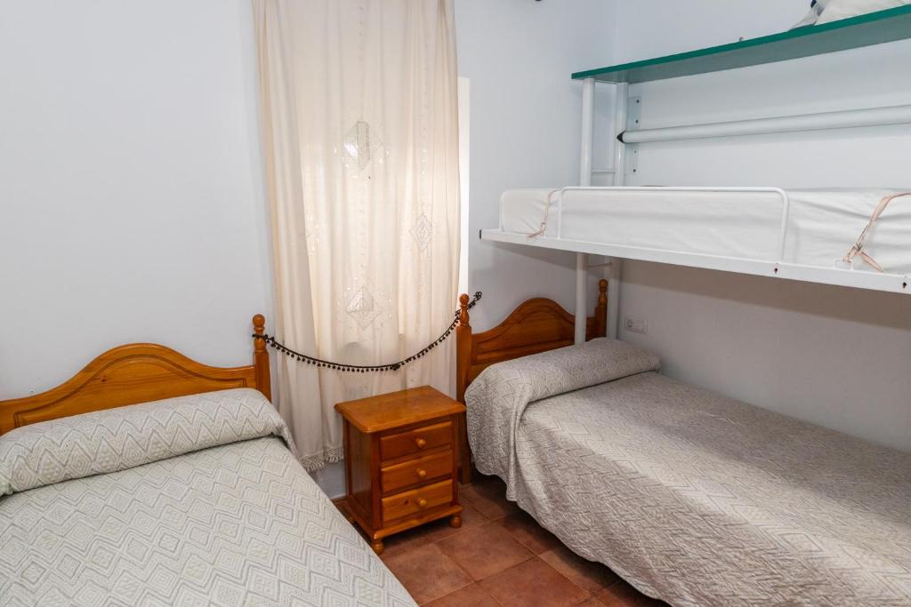 a bedroom with two beds and a shelf at Casa Marinero - Patio Andaluz in Barbate