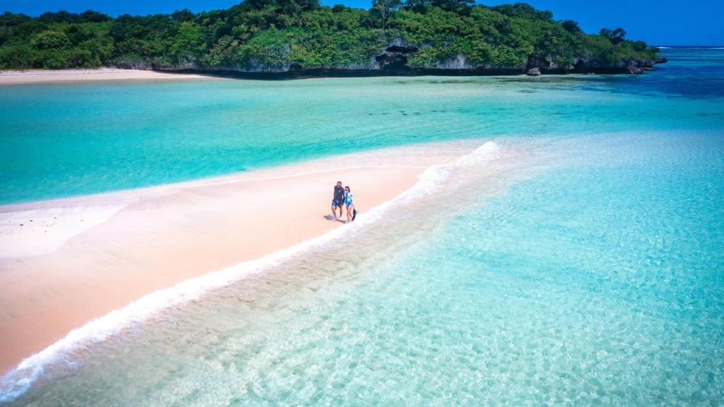 two people walking on a beach in the ocean at InterContinental Fiji Golf Resort & Spa, an IHG Hotel in Natadola