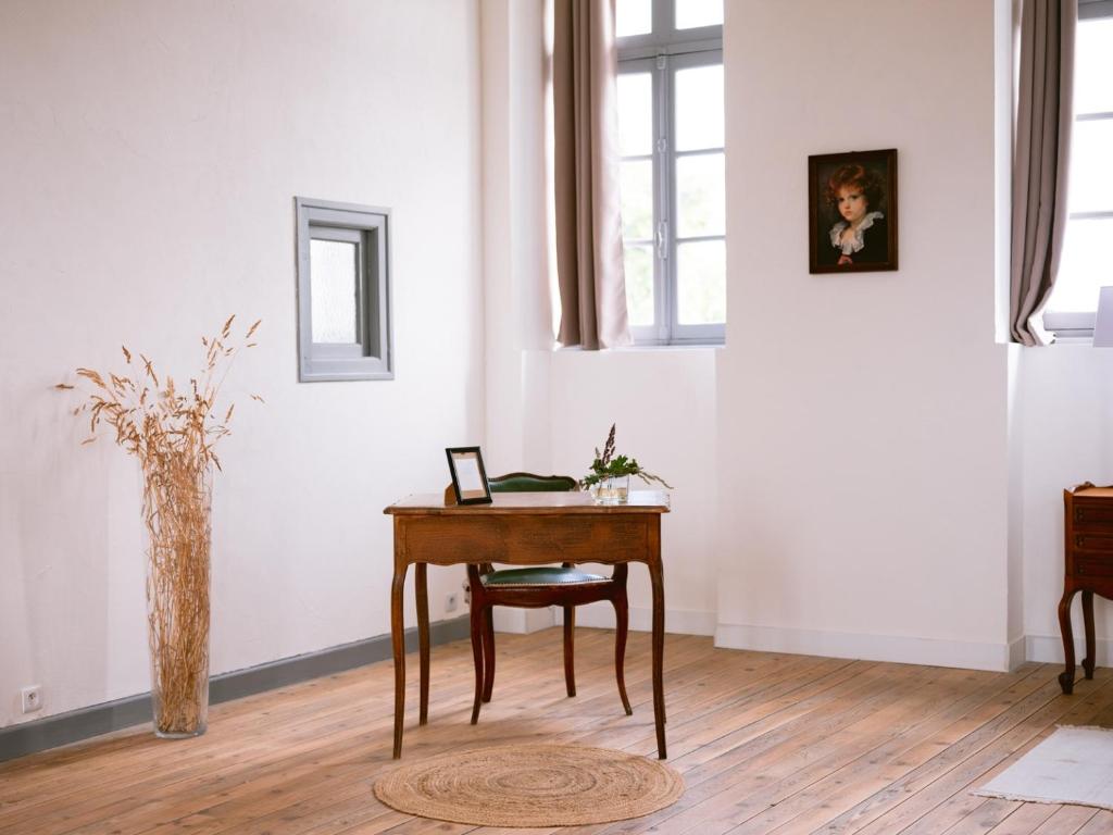 uma secretária num quarto com um vaso e uma mesa em Demeure de kergoguen em Plougonver
