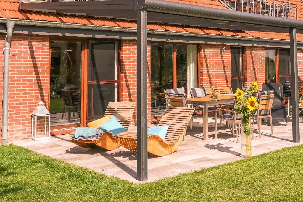un patio cubierto con sillas y mesa en FEWO Wiesenschlummerland Harriersand en Schwanewede