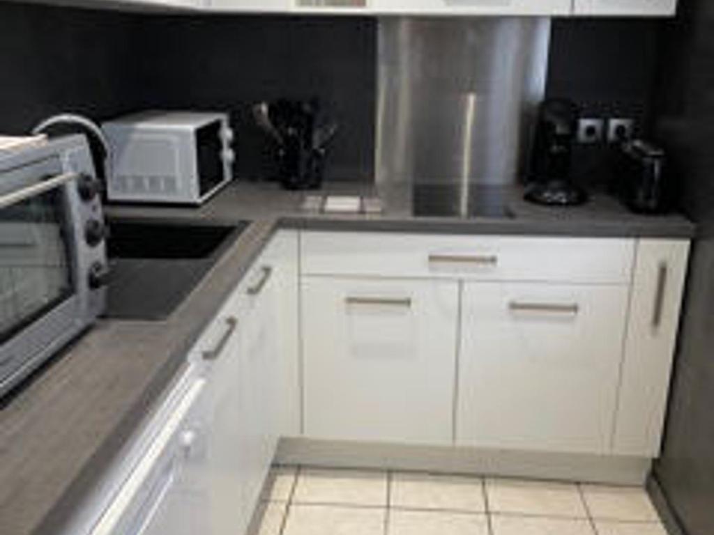 eine Küche mit weißen Schränken und einer Mikrowelle in der Unterkunft Appartement Aix-les-Bains, 1 pièce, 3 personnes - FR-1-617-6 in Aix-les-Bains