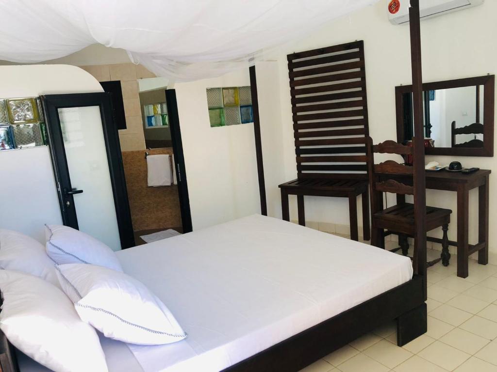 a bedroom with a bed and a table and a chair at Hôtel Tropicana Majunga in Mahajanga