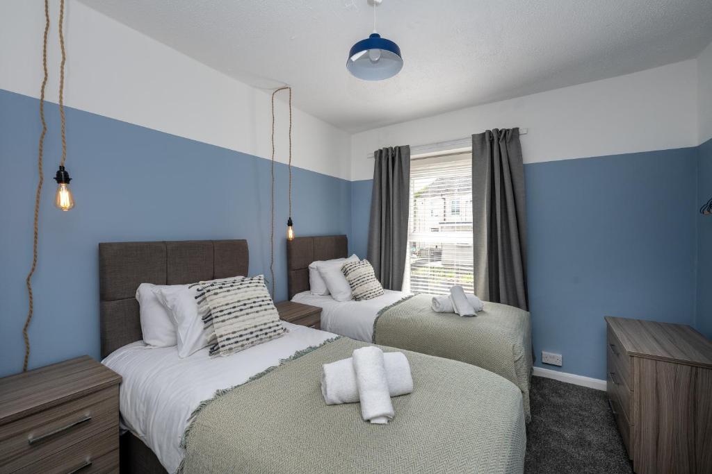 Duas camas num quarto com paredes azuis em Stay at the Marine House - TV in every bedroom! em Morriston