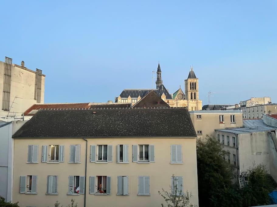 a white building with a black roof in a city at Saint-Denis Basilique : centre historique in Saint-Denis