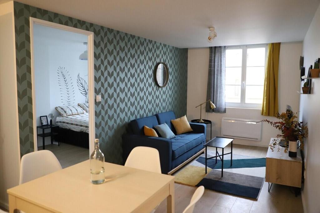 a living room with a blue couch and a bedroom at Le 23 de Louis in Limoges