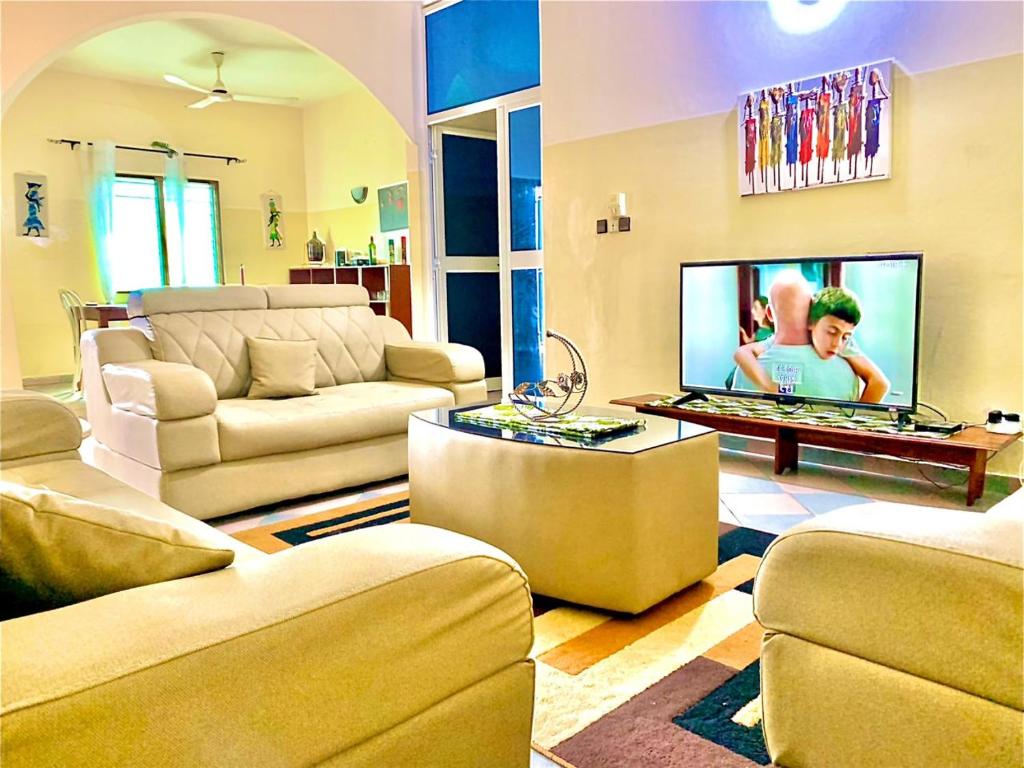 ein Wohnzimmer mit Sofas und einem Flachbild-TV in der Unterkunft Yiri Guest 1 Fidjrossè Plage in Cotonou