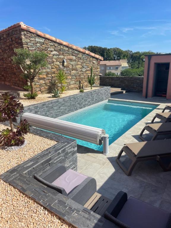 een zwembad in een achtertuin met stoelen en een zwembad bij La Bergerie Furiani avec piscine privée Residence Digoune in Furiani