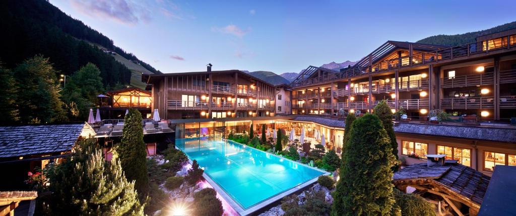 une vue sur l'extérieur d'un hôtel avec une piscine dans l'établissement Hotel Quelle Nature Spa Resort, à Santa Maddalena in Casies