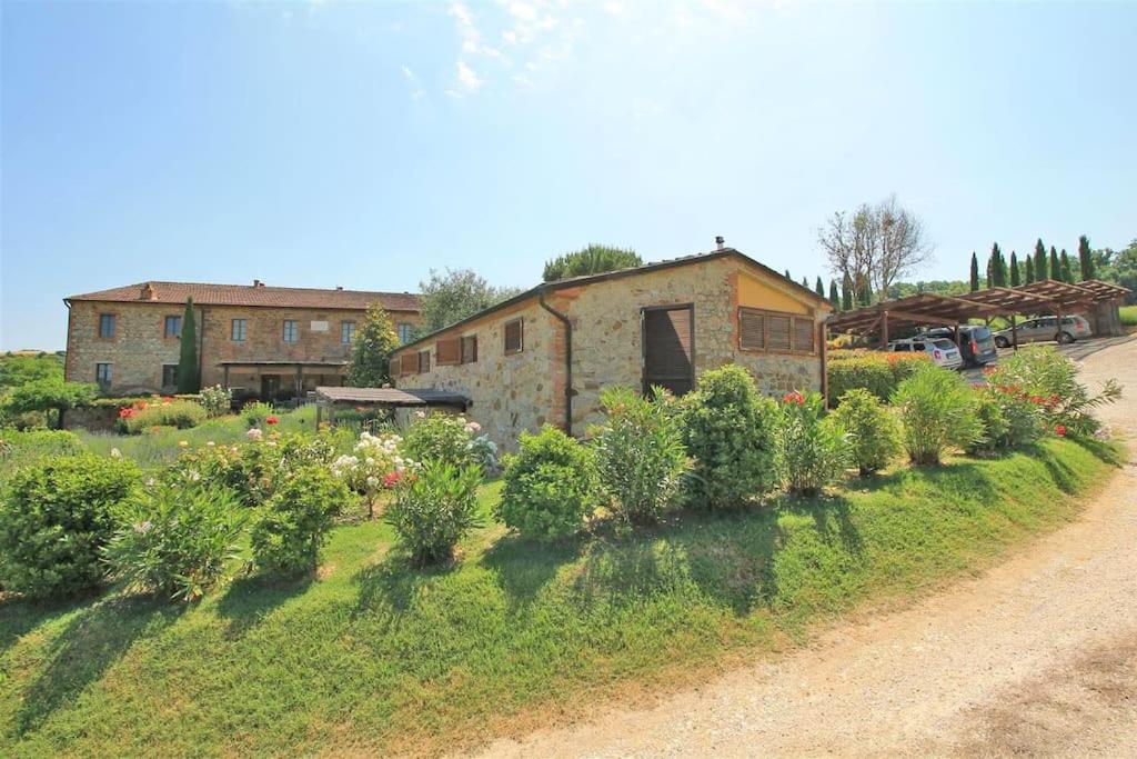 un jardin avec des buissons et un bâtiment en arrière-plan dans l'établissement Casa di campagna in Podere con piscina, à Torrita di Siena