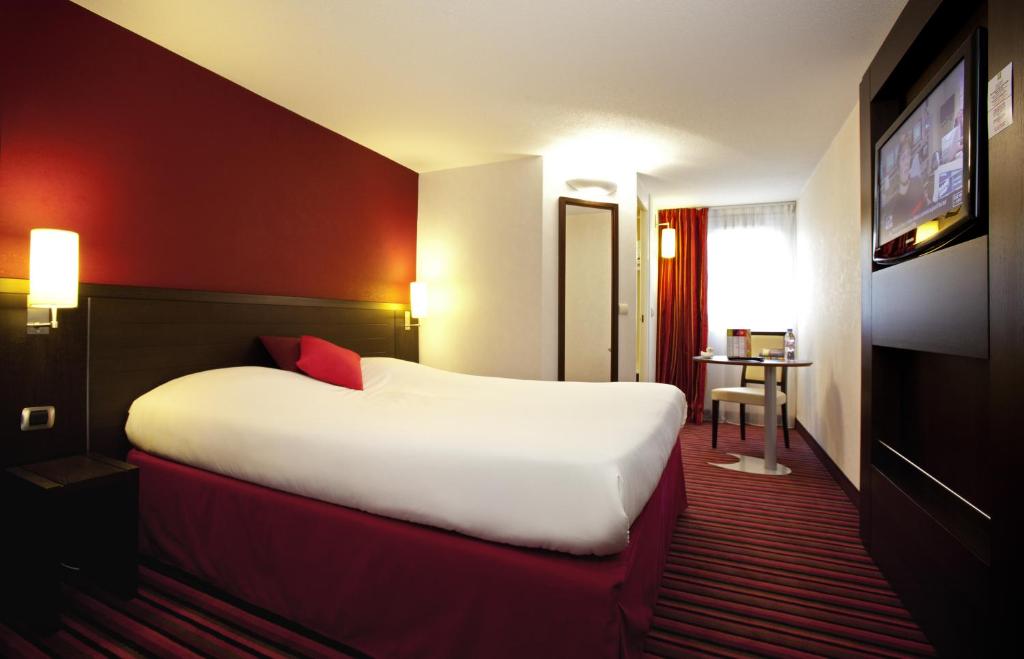 a hotel room with a large bed and a television at ibis Styles Belfort Centre in Belfort