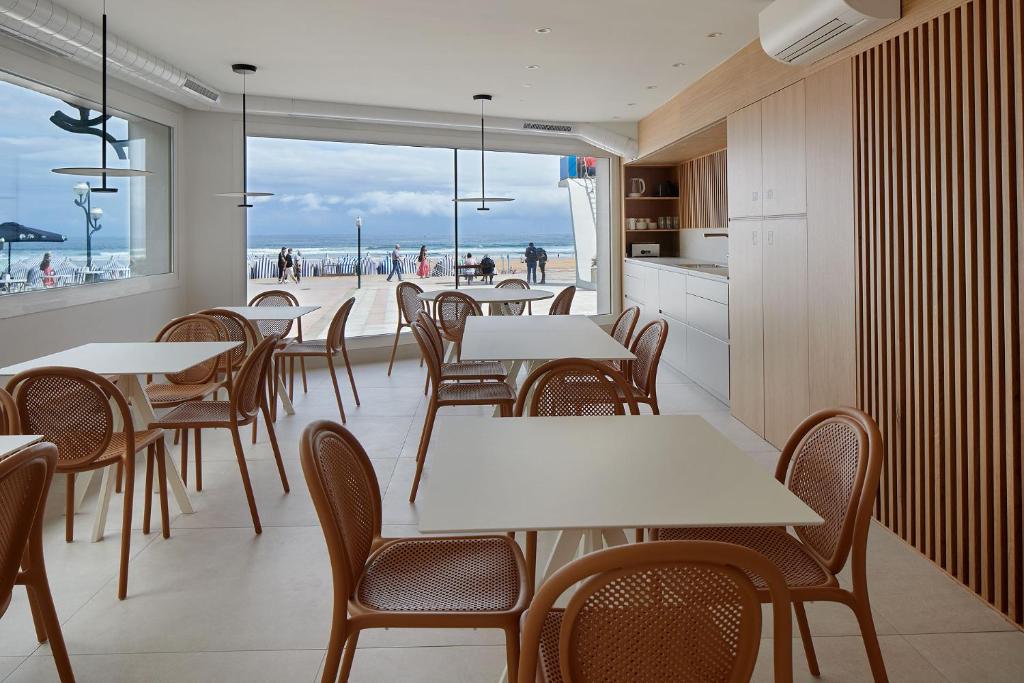 ein Restaurant mit Tischen und Stühlen und Blick auf den Strand in der Unterkunft Kein Hostel in Zarautz