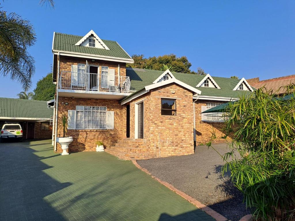 a brick house with a balcony on the side of it at Courtlyguesthouse in eMalahleni