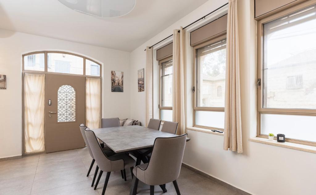 - une salle à manger avec une table, des chaises et des fenêtres dans l'établissement Vacation Apartments In The Heart Of Nachlaot, à Jérusalem
