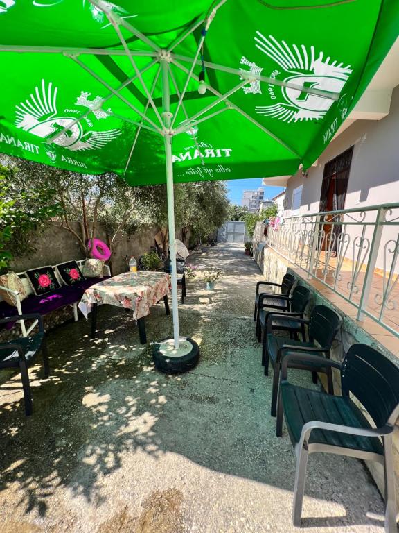 a group of tables and chairs under a green umbrella at Holiday Home in Vlorë