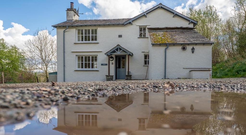 a white house with a reflection in a puddle at Hilltop in Far Sawrey