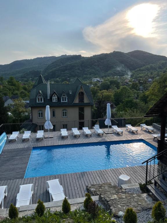 a swimming pool with lounge chairs and a house at Гірський узвіз in Vizhenka