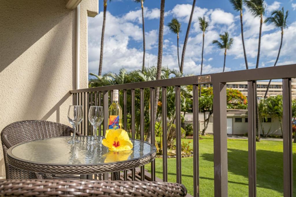 - une table avec des verres à vin et une fleur sur le balcon dans l'établissement Kihei Akahi D-104, à Wailea