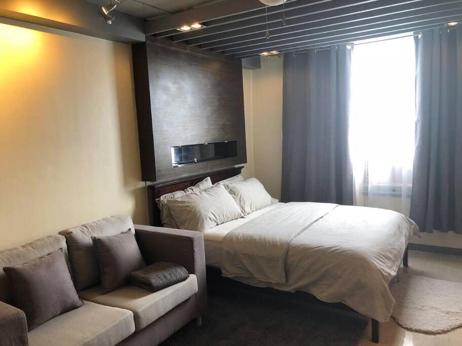 a bedroom with a large bed and a couch at Cozy Apartment for travelers and homestays in Suba