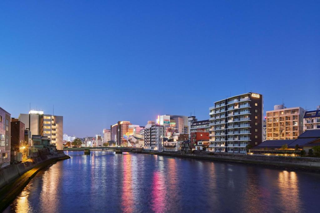 einen Fluss in einer Stadt in der Nacht mit Gebäuden in der Unterkunft ALFACIO RIVERSIDE STAY HAKATA in Fukuoka