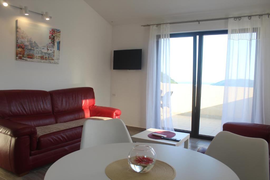 een woonkamer met een rode leren bank en een tafel bij MIA CASA Apartmens in Budva