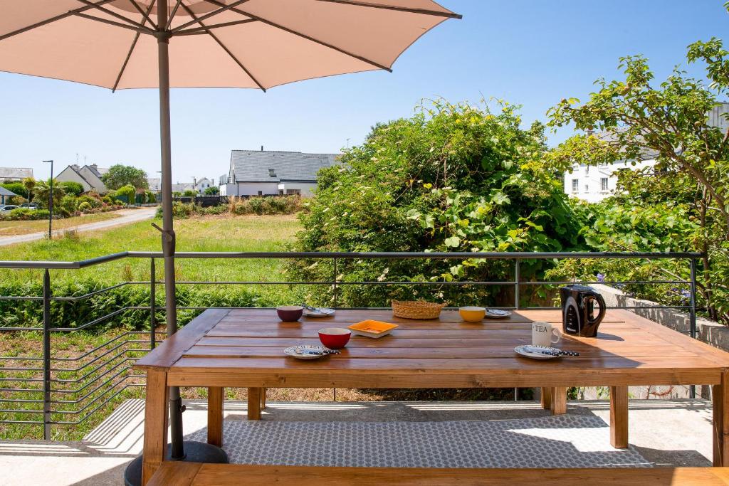 een houten tafel op een balkon met een parasol bij Paisible escale pres de la plage in Plobannalec-Lesconil