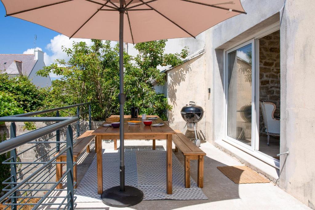 a wooden table with an umbrella on a balcony at Paisible escale pres de la plage in Plobannalec-Lesconil