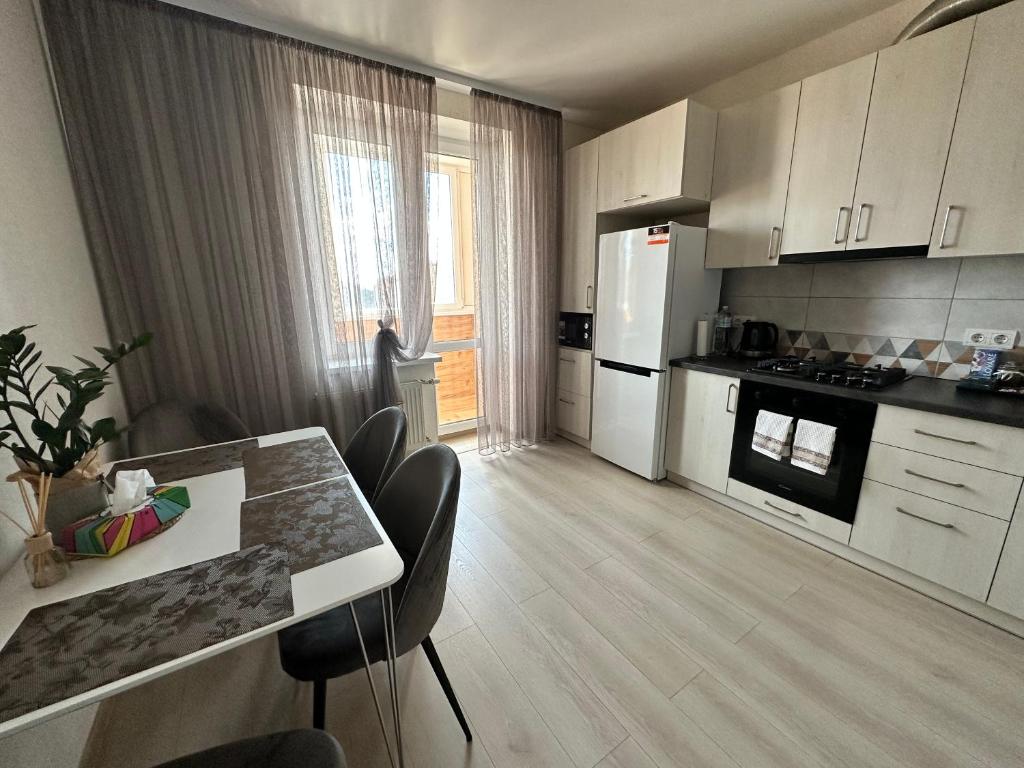 a kitchen with white cabinets and a table with chairs at Apartment, Podillya in Vinnytsya