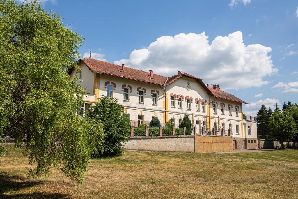 um grande edifício amarelo com árvores em frente em Pension v parku Český Šternberk em Cesky Sternberk