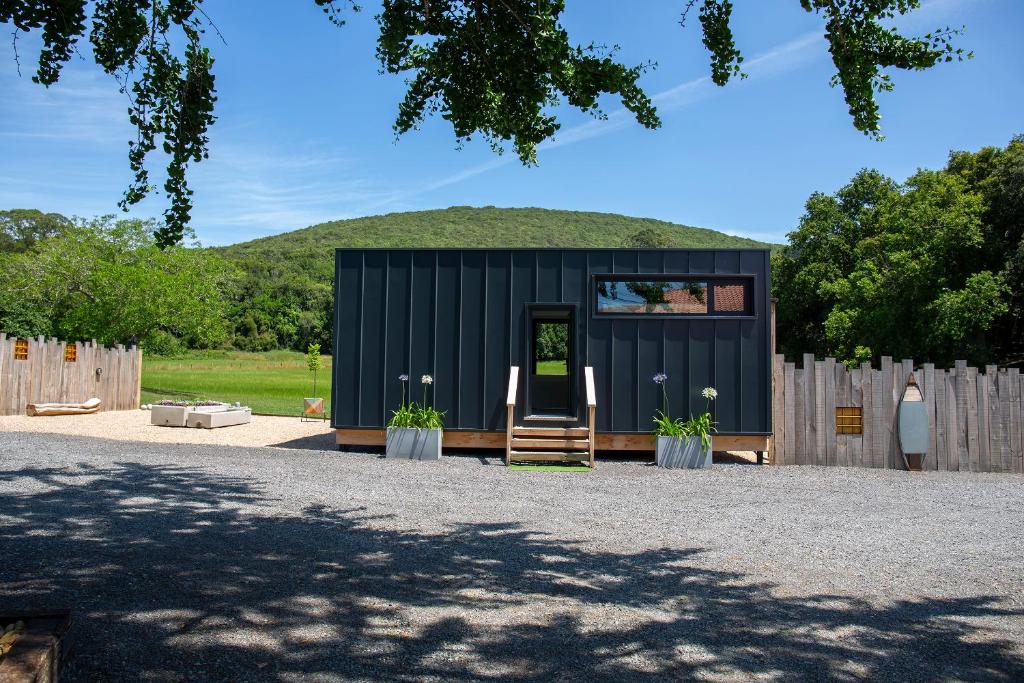 una pequeña casa negra con una colina en el fondo en VIBE LUXURY CABINS en Arnuero