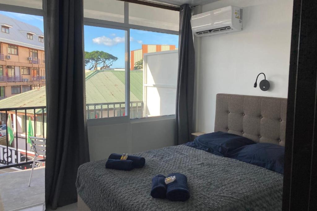 ein Schlafzimmer mit einem Bett und einem großen Fenster in der Unterkunft "Frangipani" city center room in Papeete