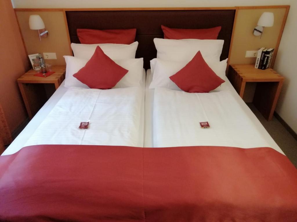 ノインブルク・フォルム・ヴァルトにあるLandhotel-Neunburgのベッドルーム1室(大型ベッド1台、赤と白の枕付)