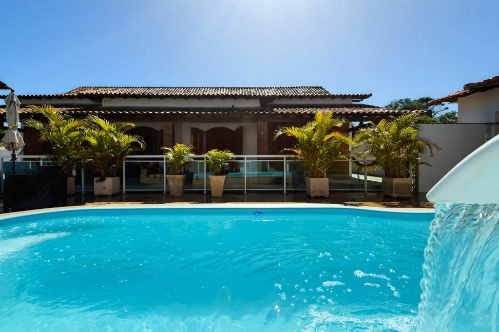 - une piscine avec une fontaine en face d'une maison dans l'établissement Village Itaúna Inn, à Saquarema