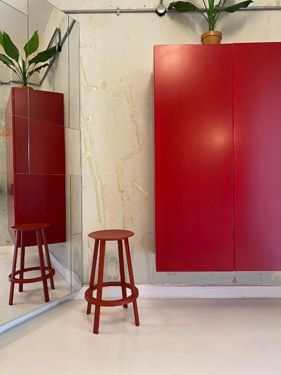 dos taburetes de madera junto a una pared roja en Trilogy Experimental, en Tesalónica