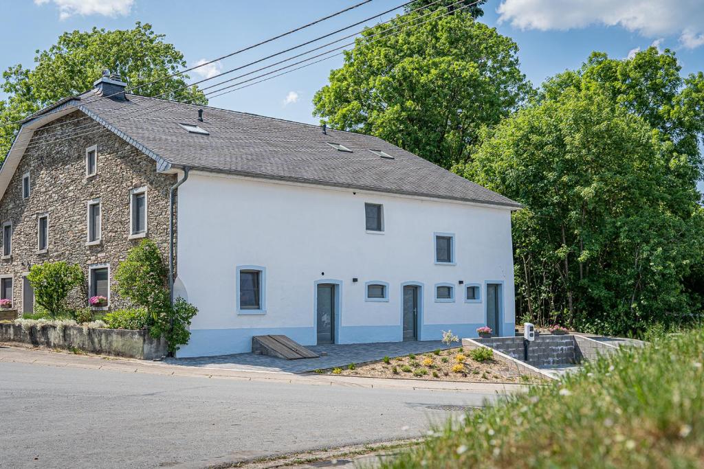 um grande edifício branco com um telhado preto em B&B - La Maison des Sottais em Burg-Reuland